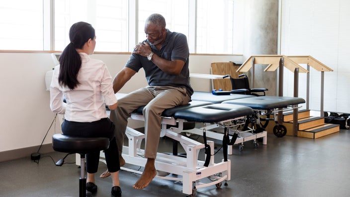 A patient explaining their shoulder pain to a physical therapist.