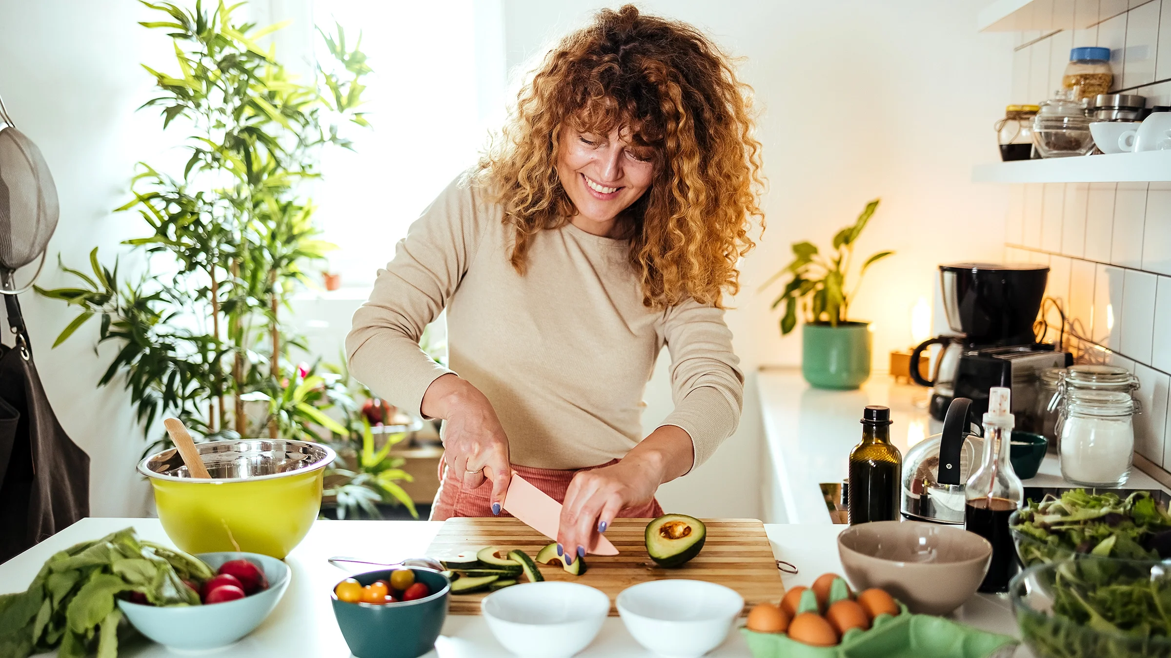 A woman in a kitchen slices an avocado, one of several foods that can lower cortisol levels.