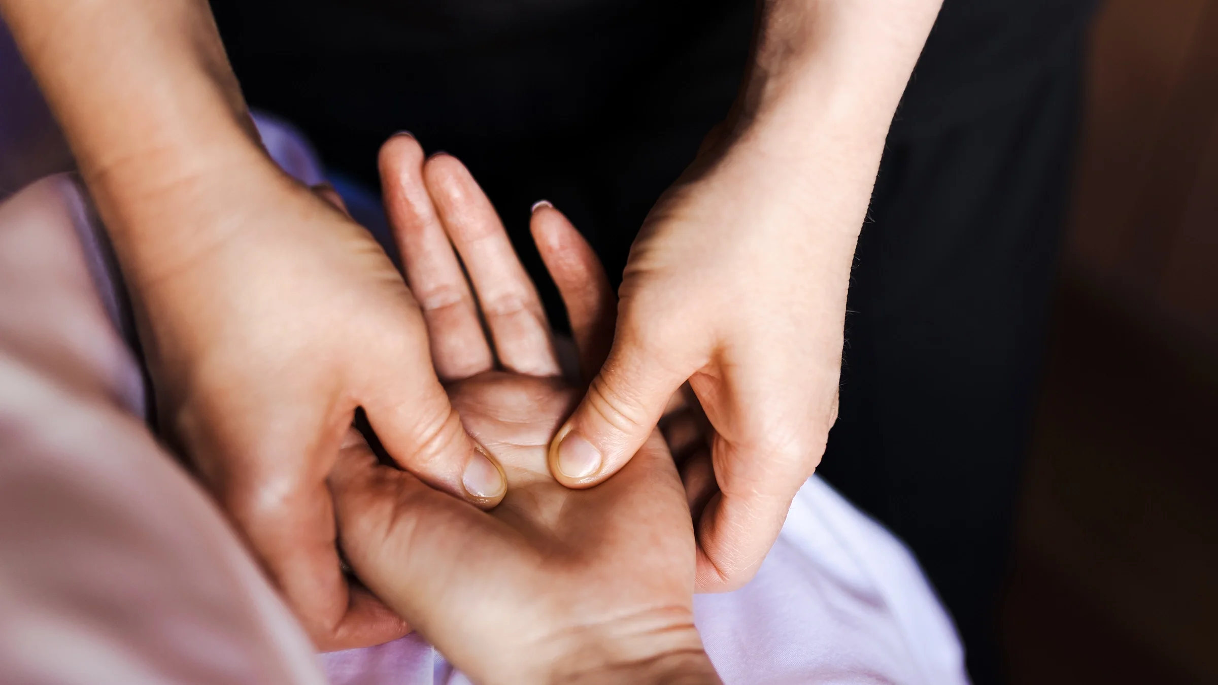 A person is massaging a pressure point on the palm of someone’s hand.