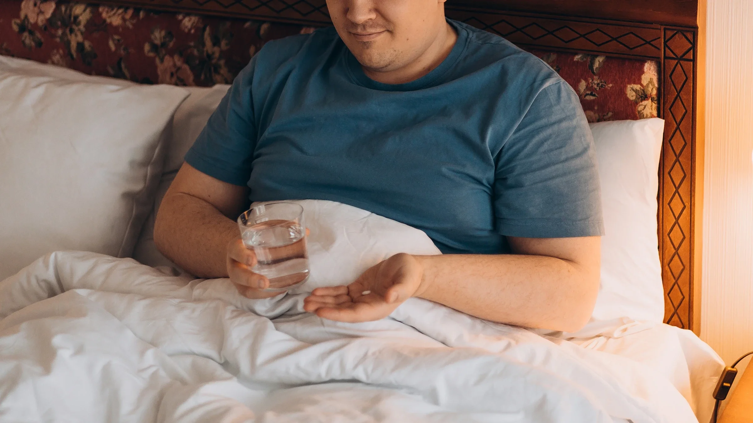 A man prepares to take medication with a glass of water.