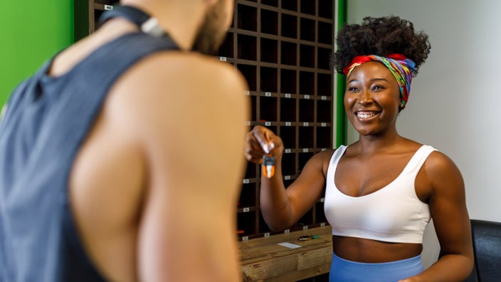 A gym receptionist handing keys to a member.