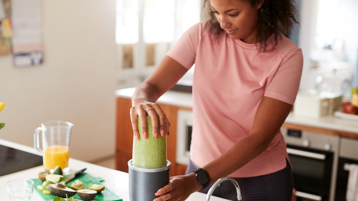 A woman makes a green smoothie. You can have soft foods like smoothies after a root canal.