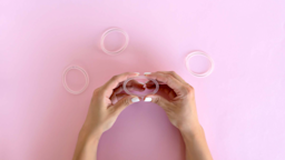 Hand reaching into frame squeezing a vaginal ring into an oval shape. There are three other clear vaginal rings surrounding the light pink background.
Irina Chetverikova/iStock via Getty Images