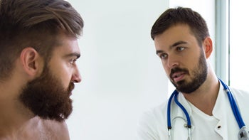 Mens health: breasts: shirtless patient talking to doctor 1142896323