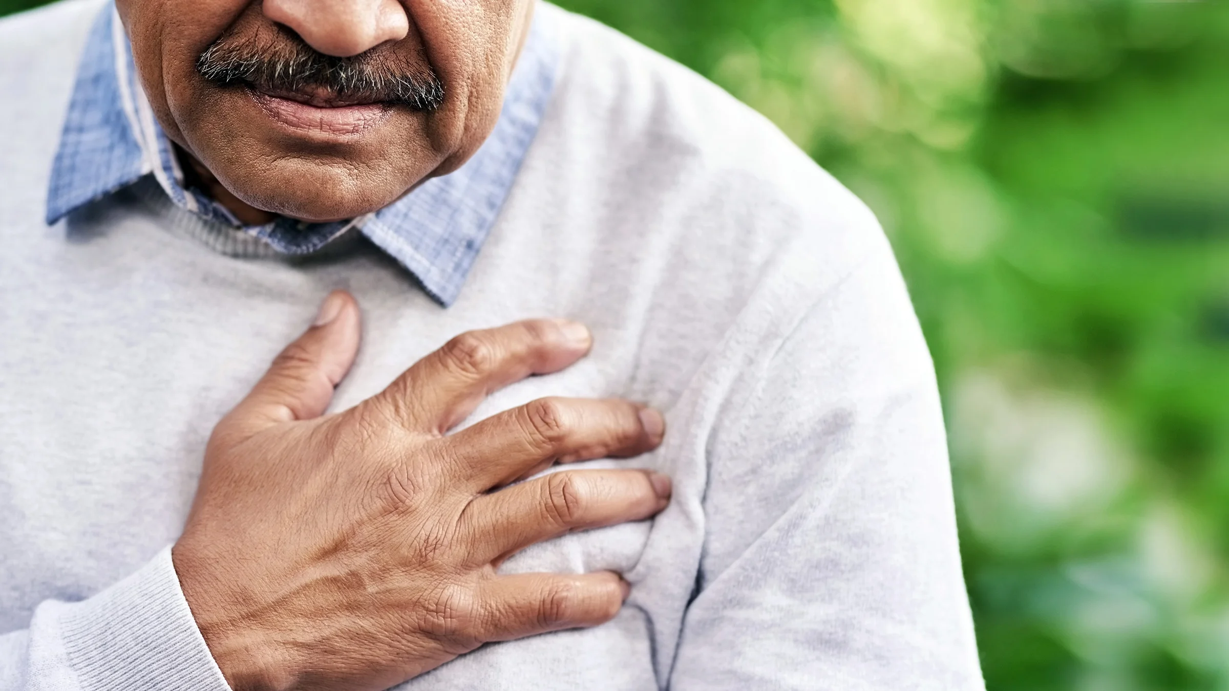 A man clutches his chest in discomfort.