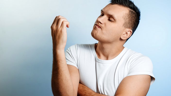 A man looks down at his nails. Several things can cause yellow nails, such as medications, health conditions, and nail polish.