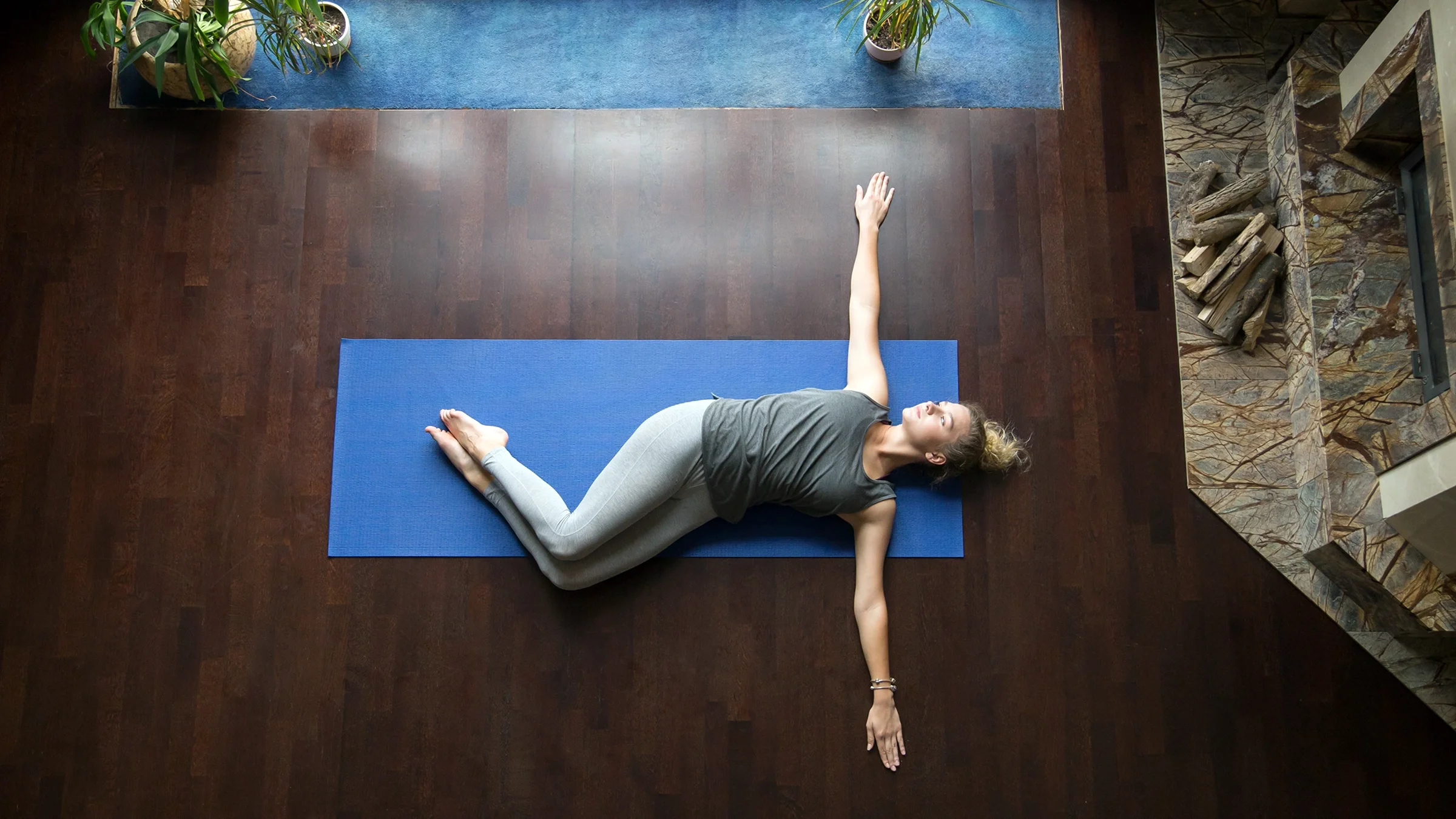 A woman does a supine twist on a yoga mat at home.
