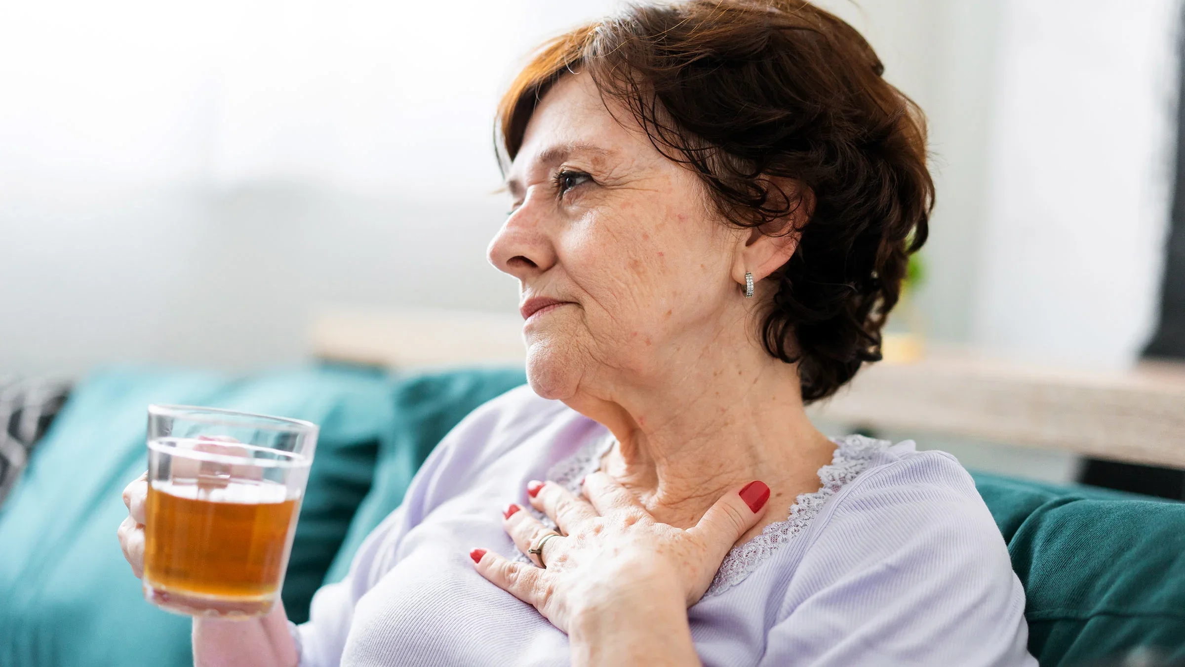 A woman sits on a sofa drinking tea. The common cold can lead to fever, inflammation, and dehydration, which can increase your heart rate.
andreswd/E+ via Getty Images