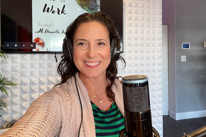 Danielle Tantone is pictured wearing headphones behind a microphone doing her podcast.