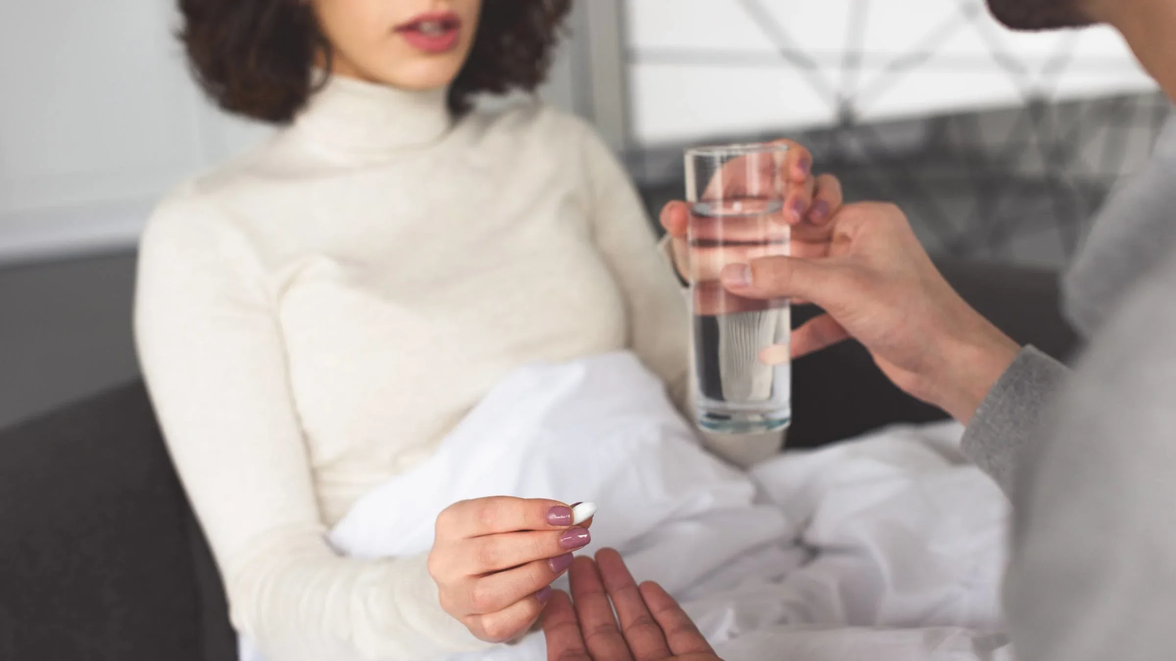 Cropped image of someone being offered a pill and water by their partner.
LightFieldStudios/iStock via Getty Images Plus