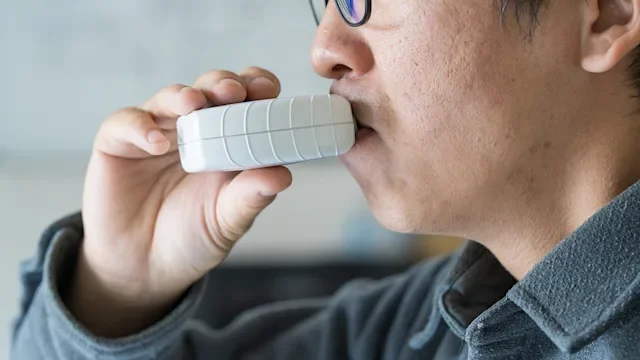Asthma: closeup man using an inhaler 1821944789