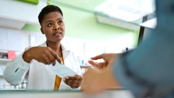 Medication Education: pharmacist handing Rx to customer 1477480018