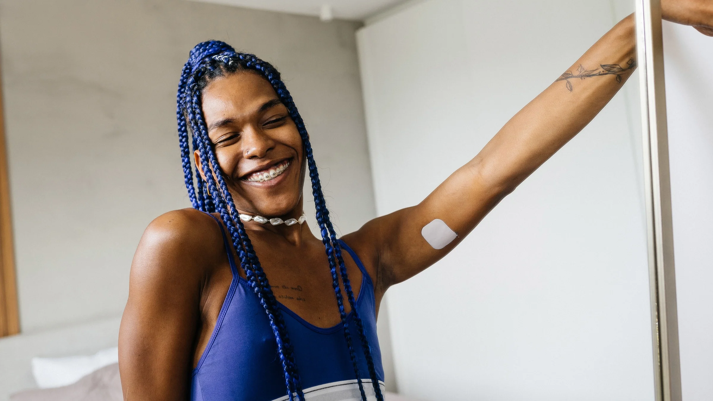 A happy transgender woman in front a mirror. There is an estrogen patch on her inner upper arm.