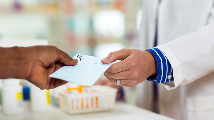 A man handing a prescription to a pharmacist