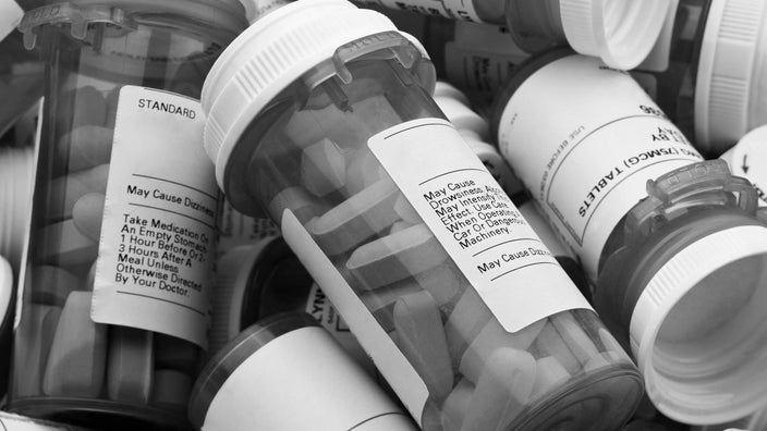 Black and white extreme close-up on a pile of prescription bottles.
