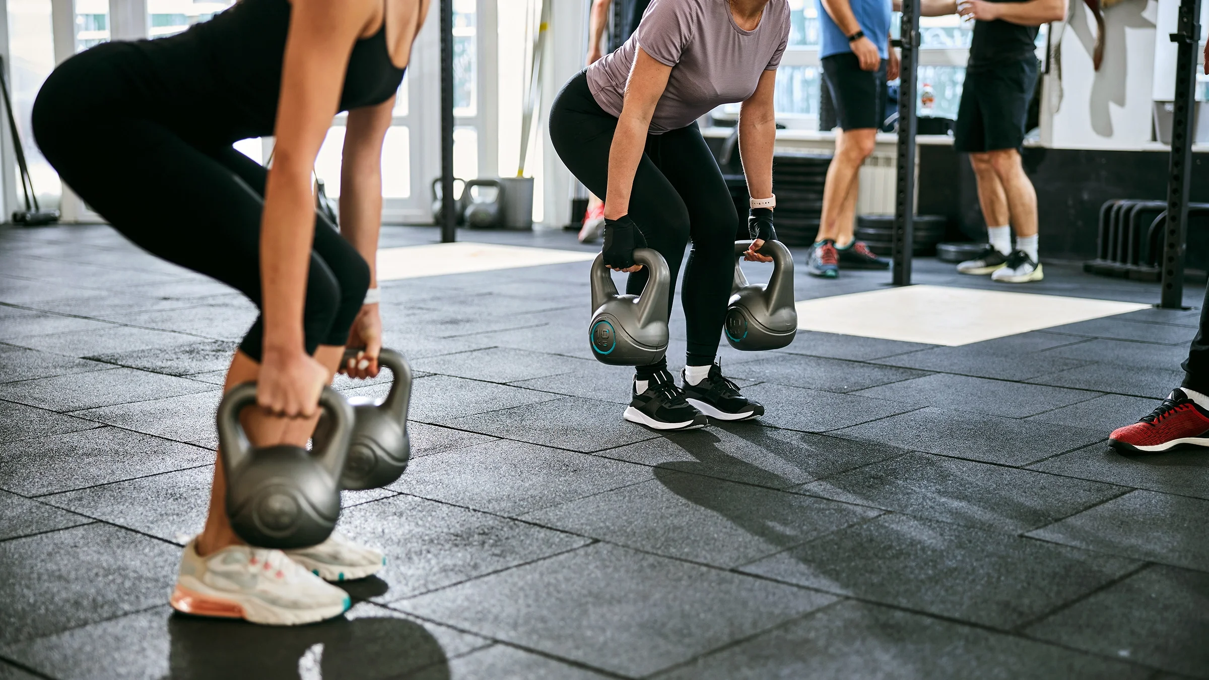 Woman doing a dead lift exercise with kettlebells at the gym.