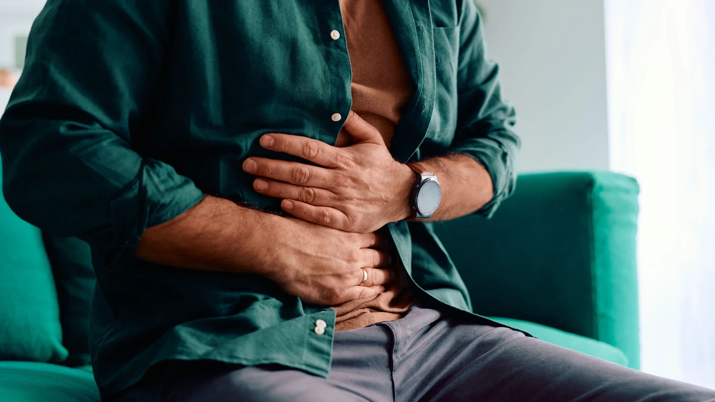 A person with an upset stomach sitting down and holding their stomach.
Igor Suka/iStock via Getty Images Plus  