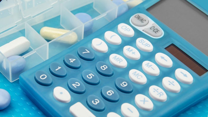 A pill container next to a calculator.