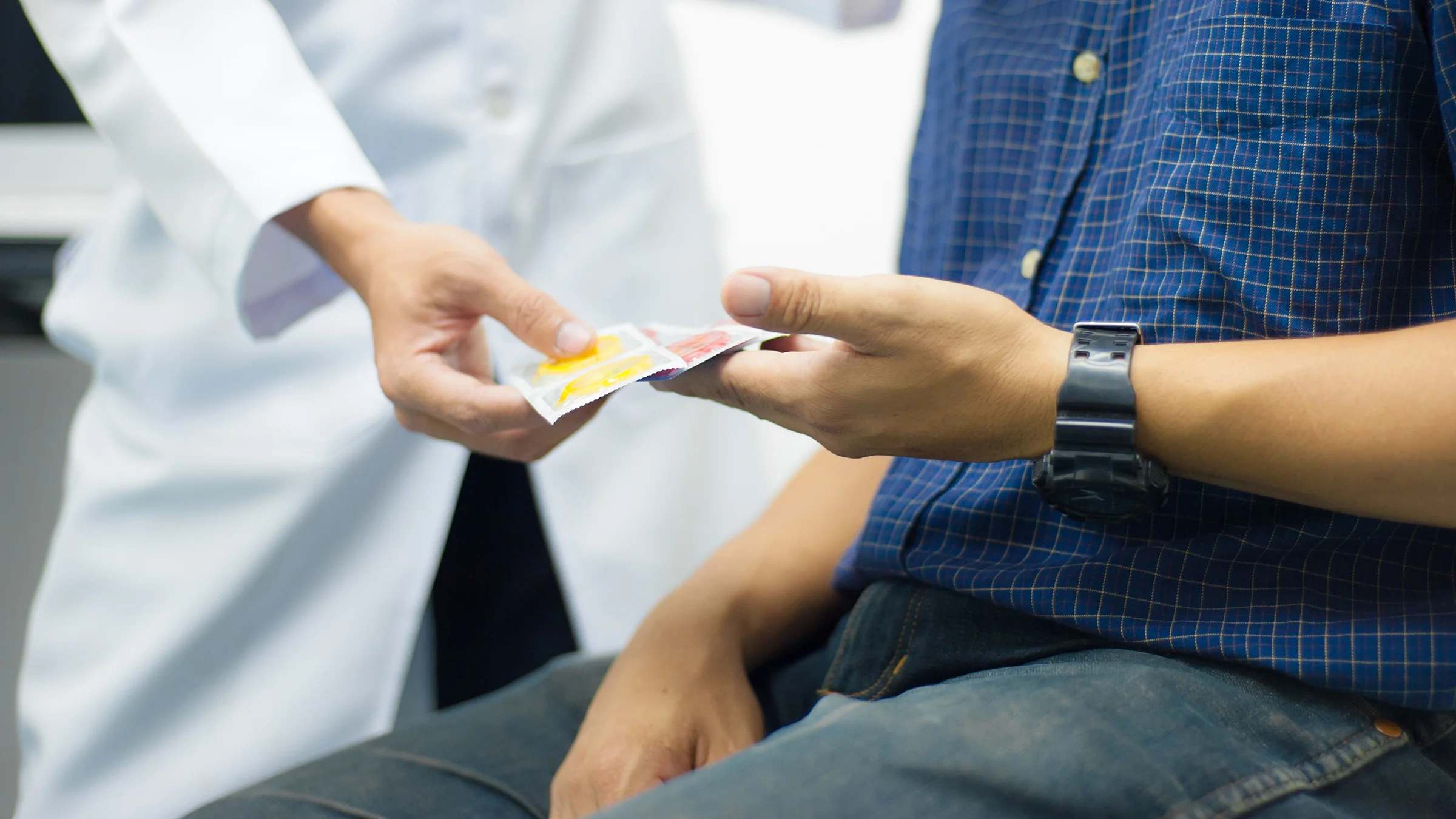 Cropped shot of a doctor handing a man a pack of condoms.