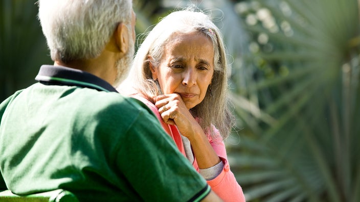 A woman sitting in the park is upset.