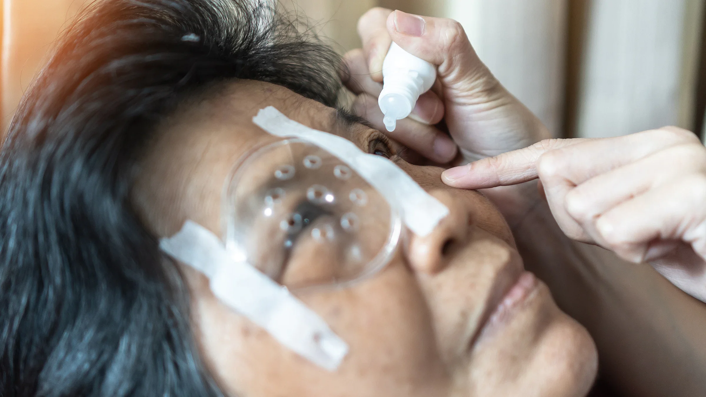 Senior woman having eye drops administered by another person.
Chinnapong/iStock via Getty Images