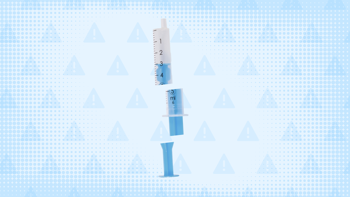 Light-blue background with texture and warning sign pattern. In the center is a blue plastic syringe cut into thirds.