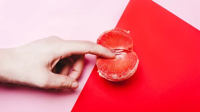 Sexual health: still life orgasm concept hand and grapefruit 1129643399
