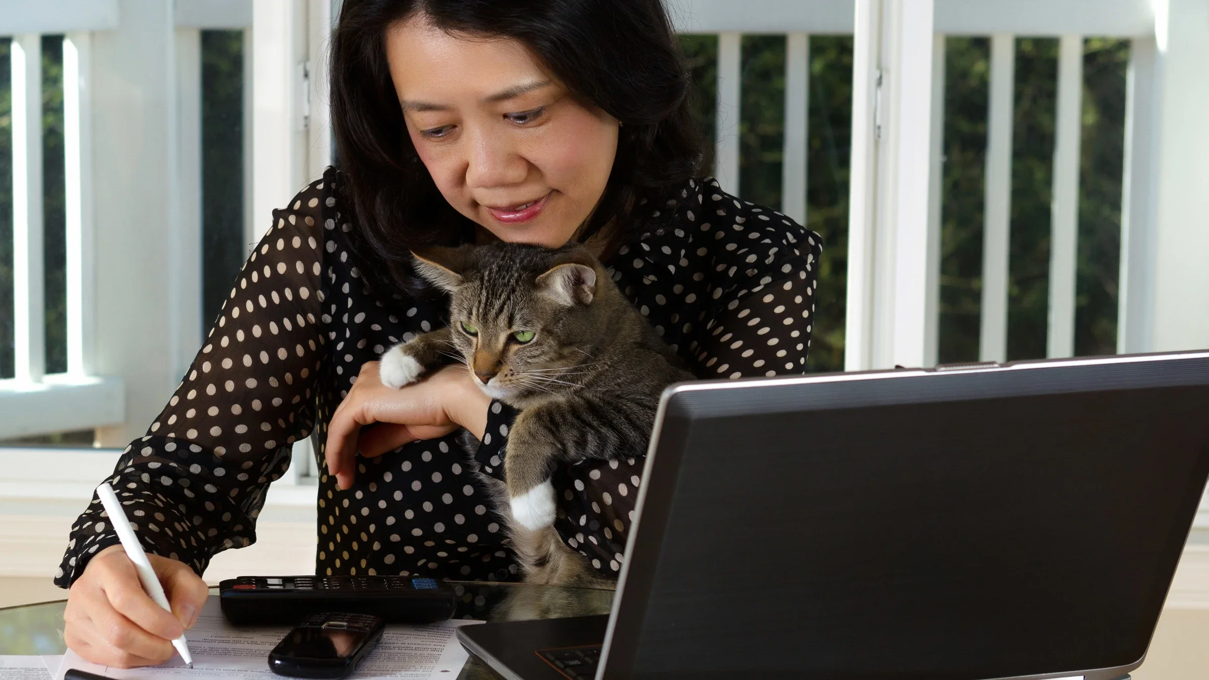 A person holding their cat while doing their taxes.
tab1962/iStock via Getty Images 