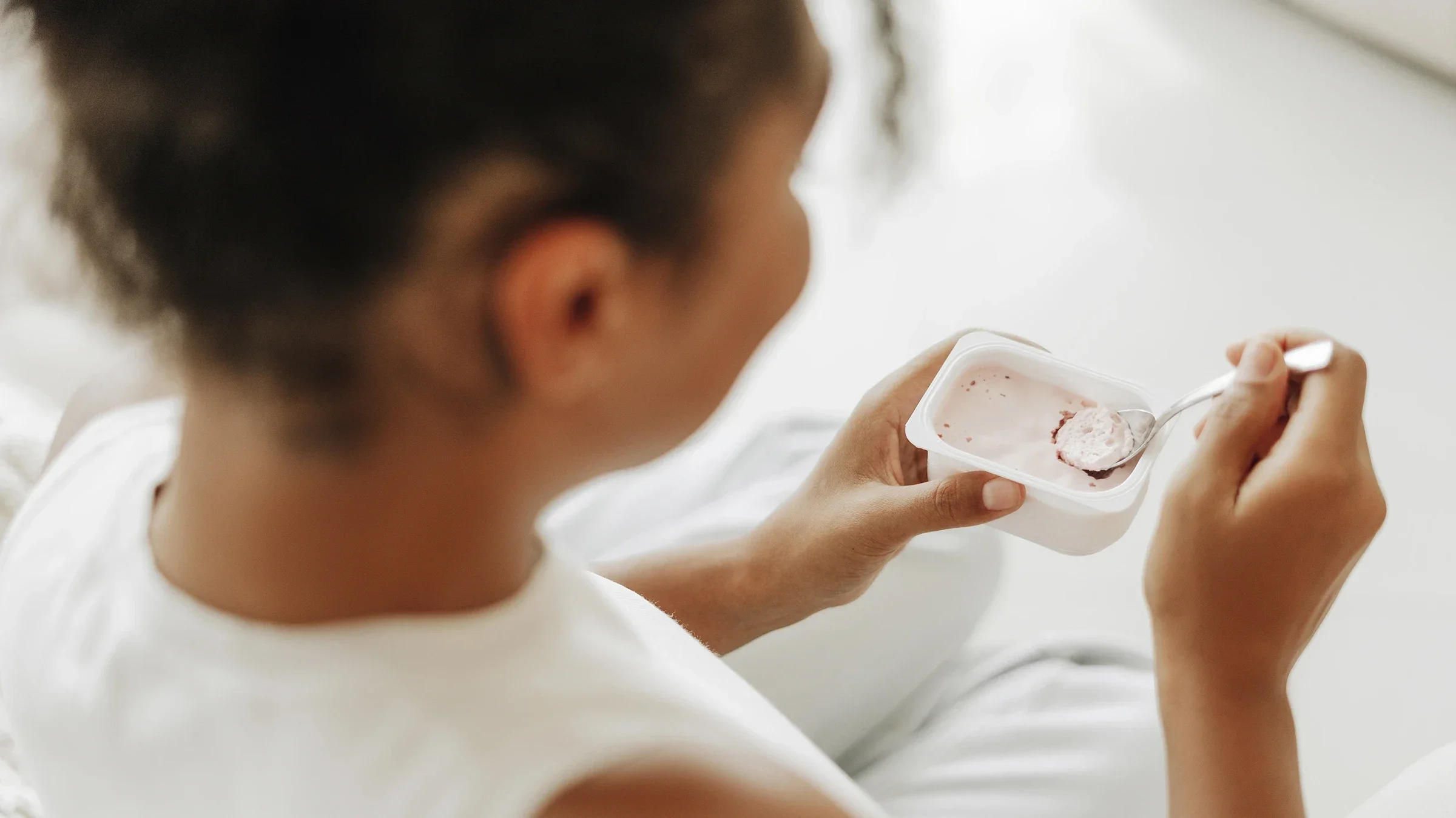 A woman eats yogurt.
/iStock via Getty Images Plus