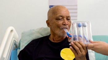 respiratory: senior man using incentive spirometer 1126858979
