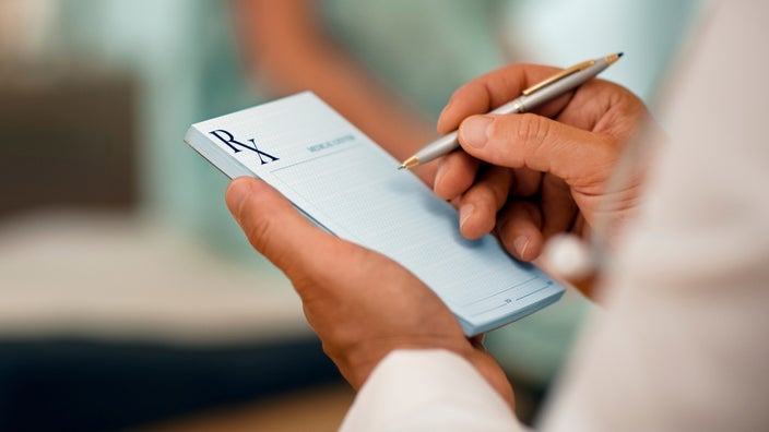 Cropped sho of someone holding a prescription pad and pen.