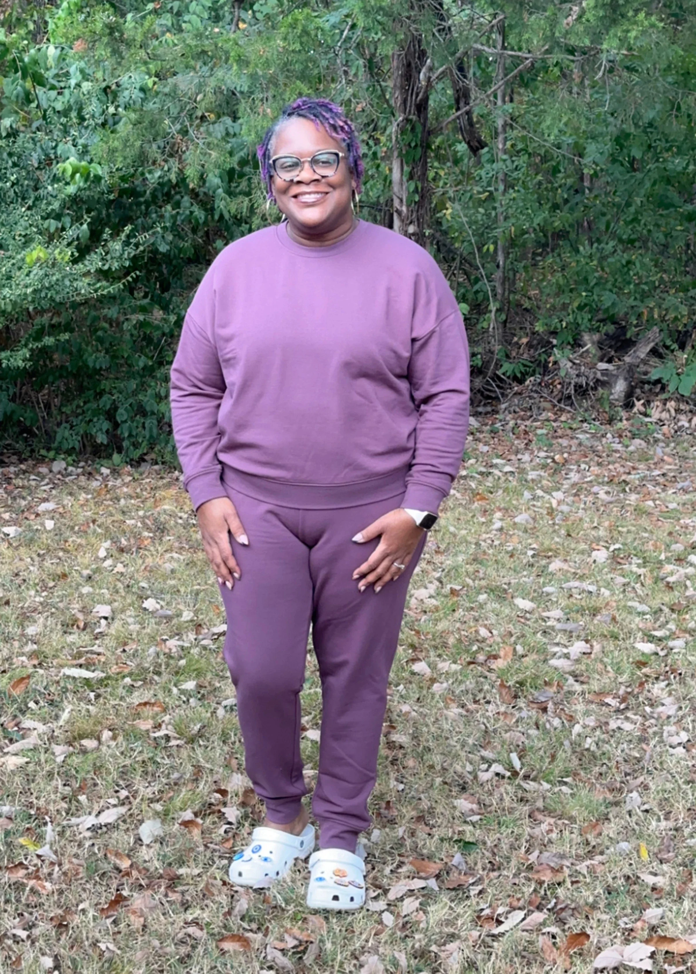 Alisha Lampley is pictured standing outdoors, wearing a purple sweatsuit.