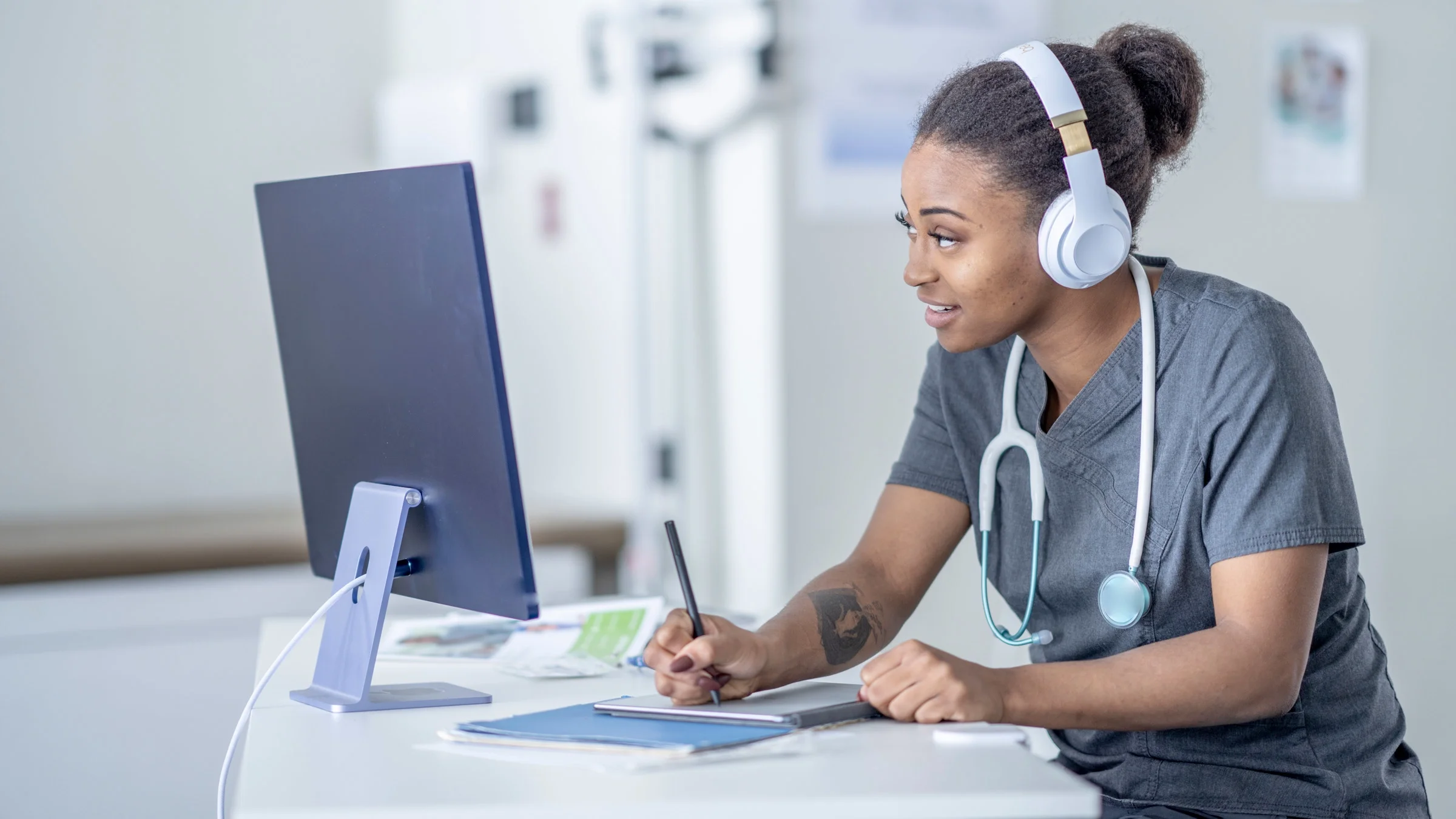 A HCP taking notes during a telehealth appointment.