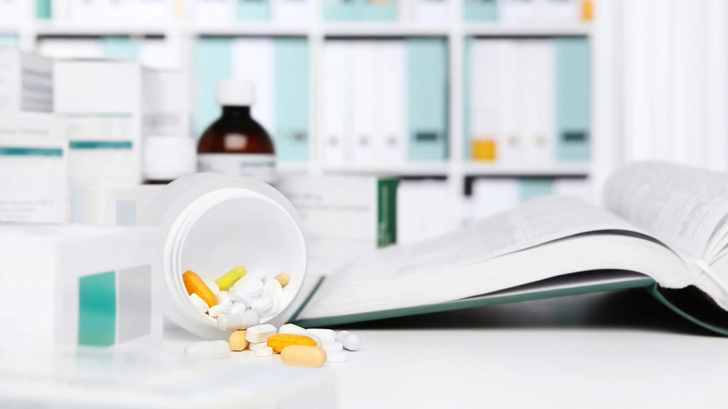 Pill bottle spilling next to an open textbook.