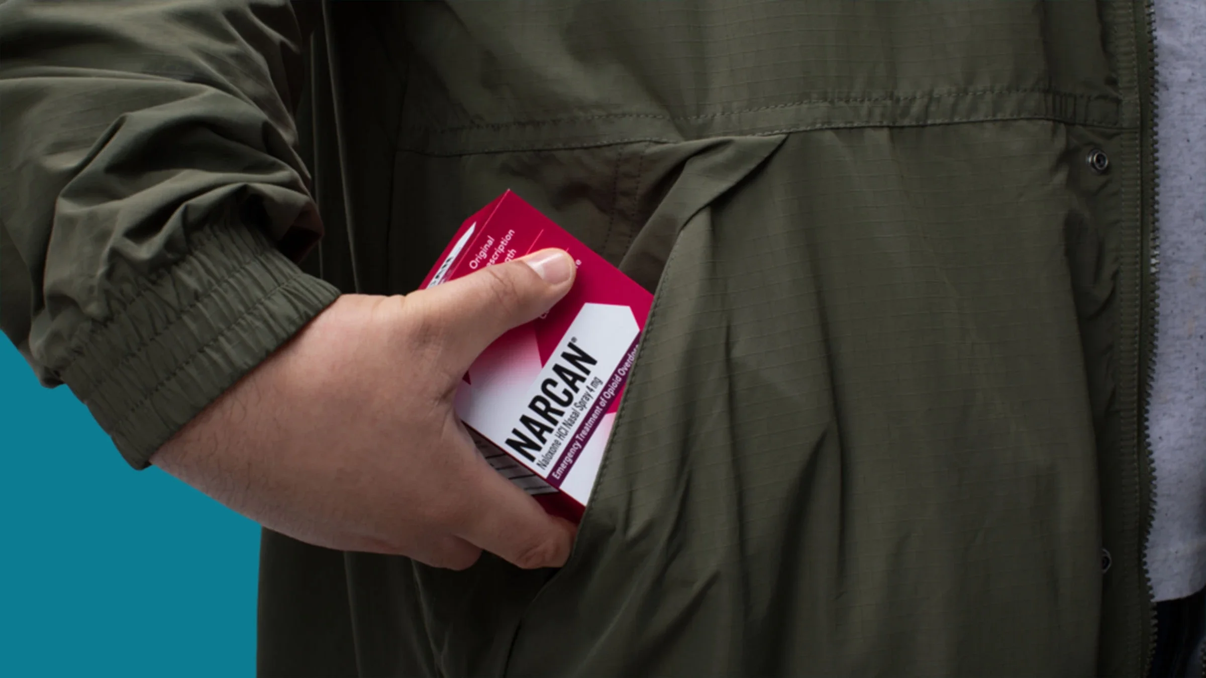 A hand places a box of Narcan in a coat pocket.