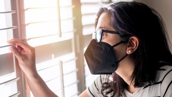 woman wearing face mask looking out window-1368116977