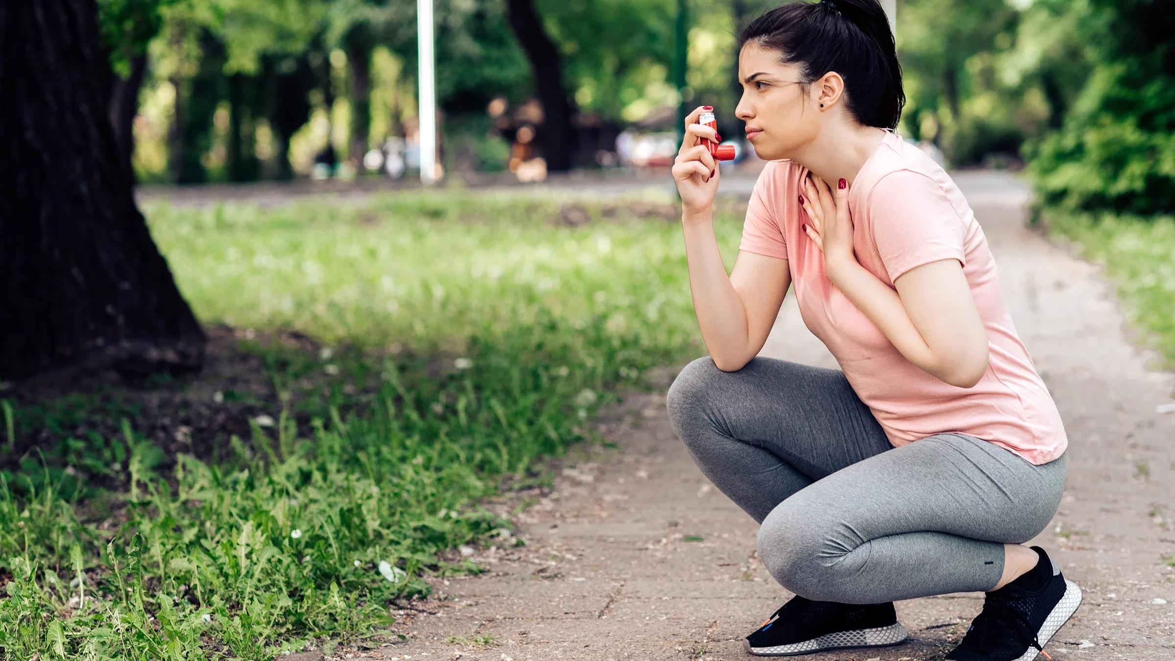 A woman squatting on the sidewalk uses her inhaler following an asthma attack.
RgStudio/E+ via Getty Images