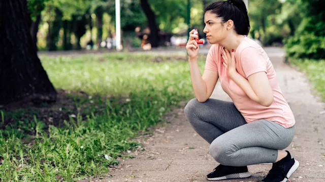 Asthma: woman using inhaler outside 1227575702