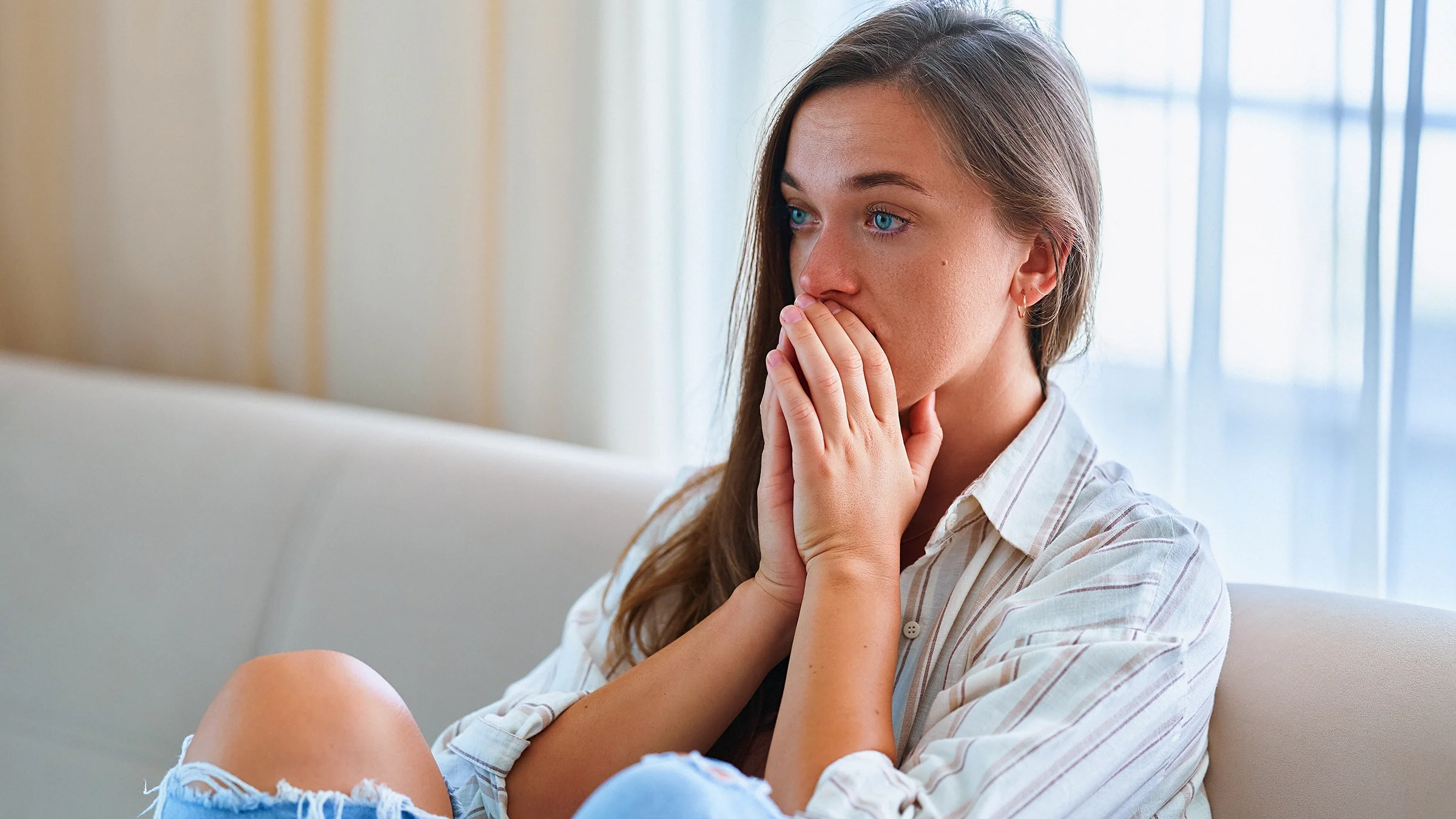An anxious woman sitting alone at home.