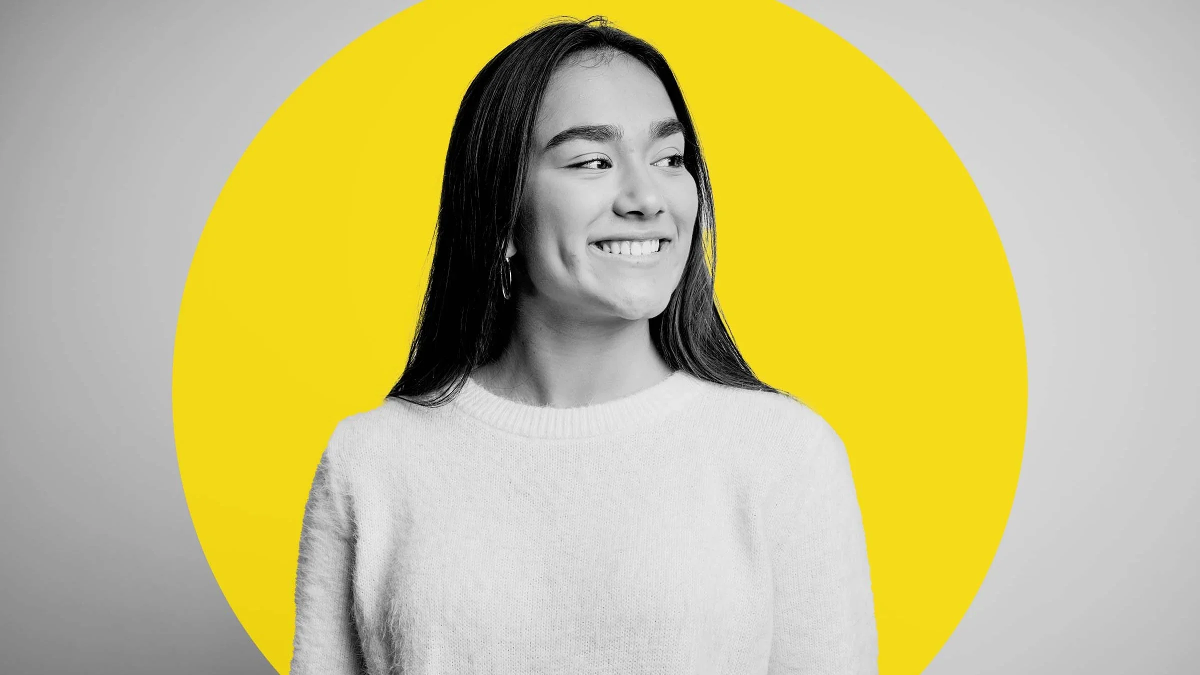 Black and white portrait of a young woman with straight hair. There is a bright yellow circle graphic added behind her.
AaronAmat/iStock via Getty Images