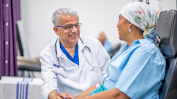 Doctor smiling and comforting their cancer patient who is receiving chemotherapy.
FatCamera/E+ via Getty Images
