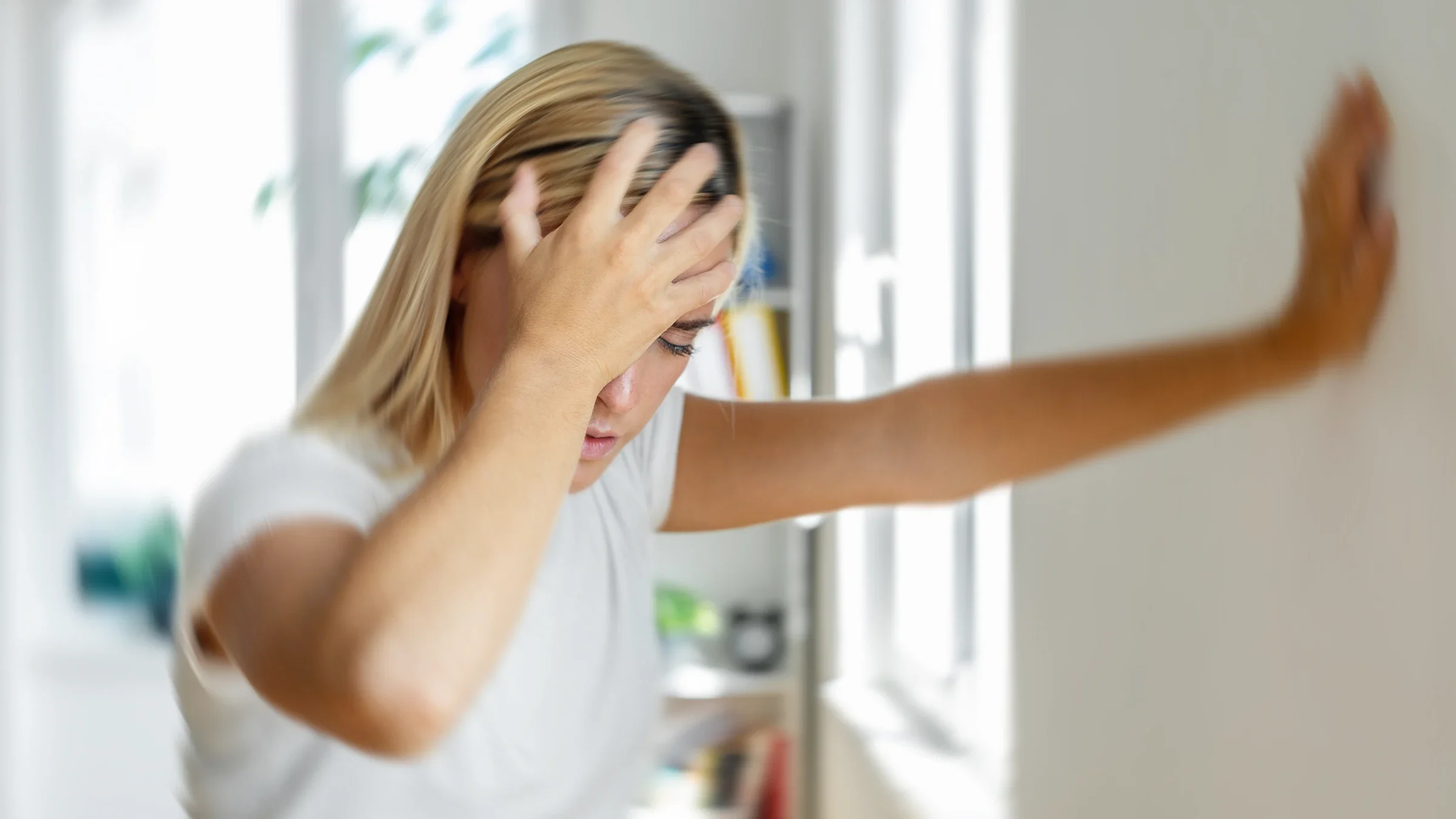 A woman grabs her forehead and leans on the wall as she experiences dizziness.
bymuratdeniz/E+ via Getty Images