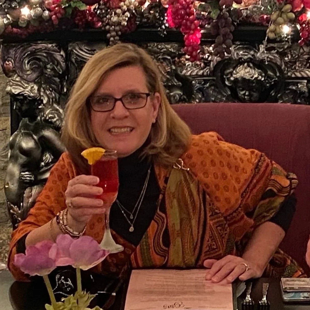 Liz Carey is pictured at a table toasting a glass with friends.
