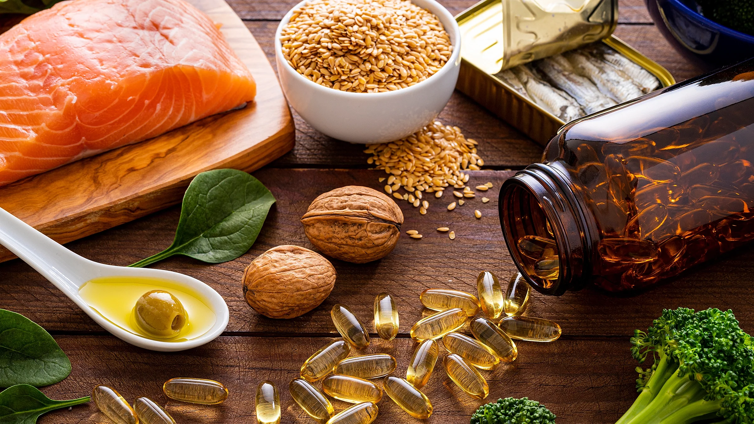Overhead of fish oil capsules surrounded by an assortment of food rich in omega-3.