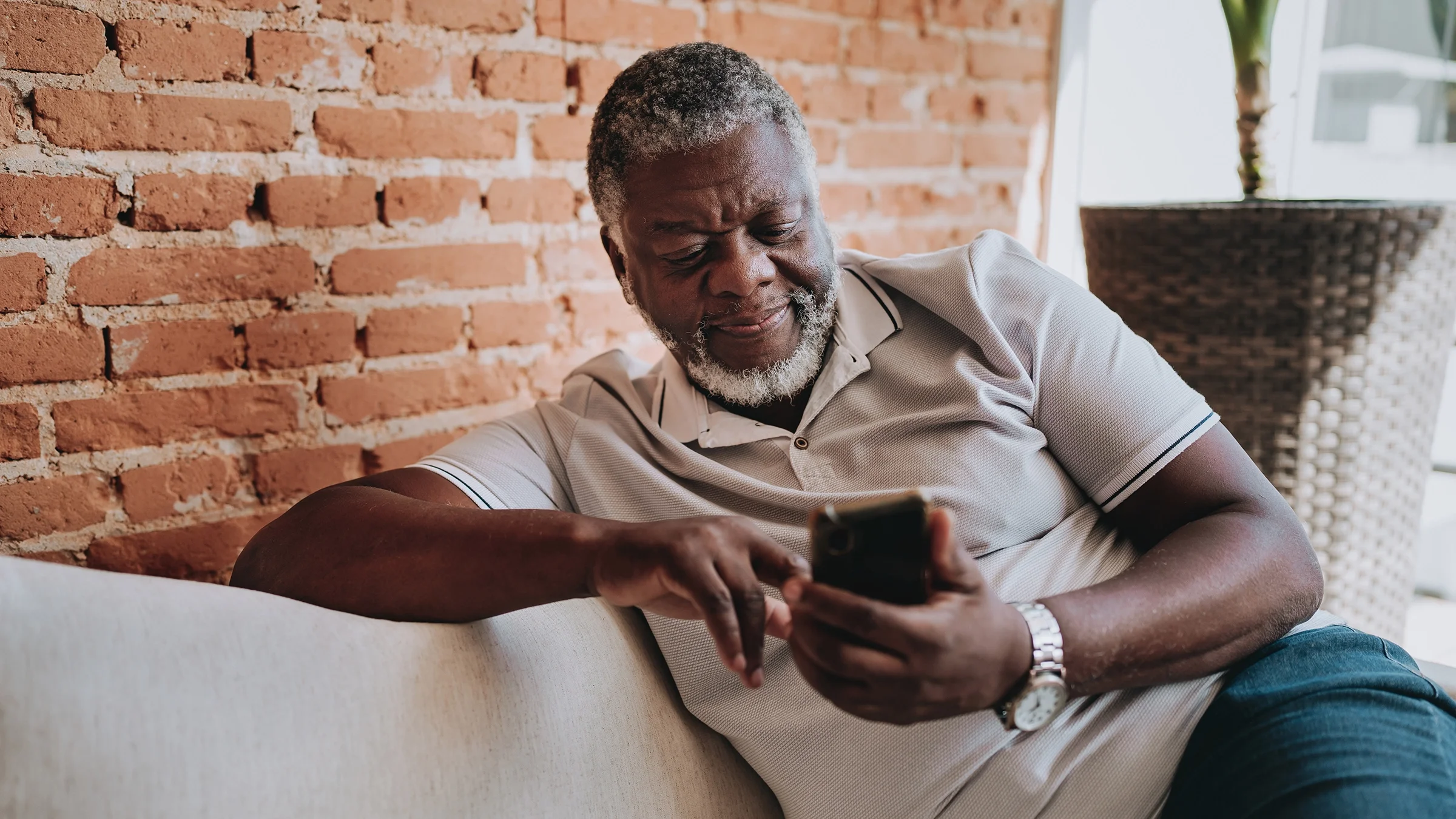 A man uses his cell phone while sitting on the couch.