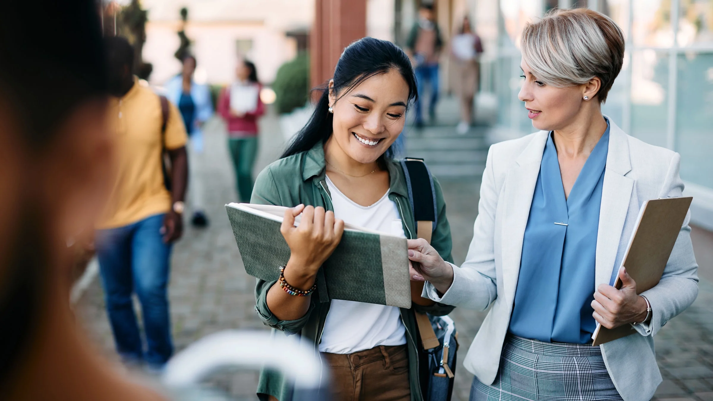 A professor and student talking as they walk around campus.
