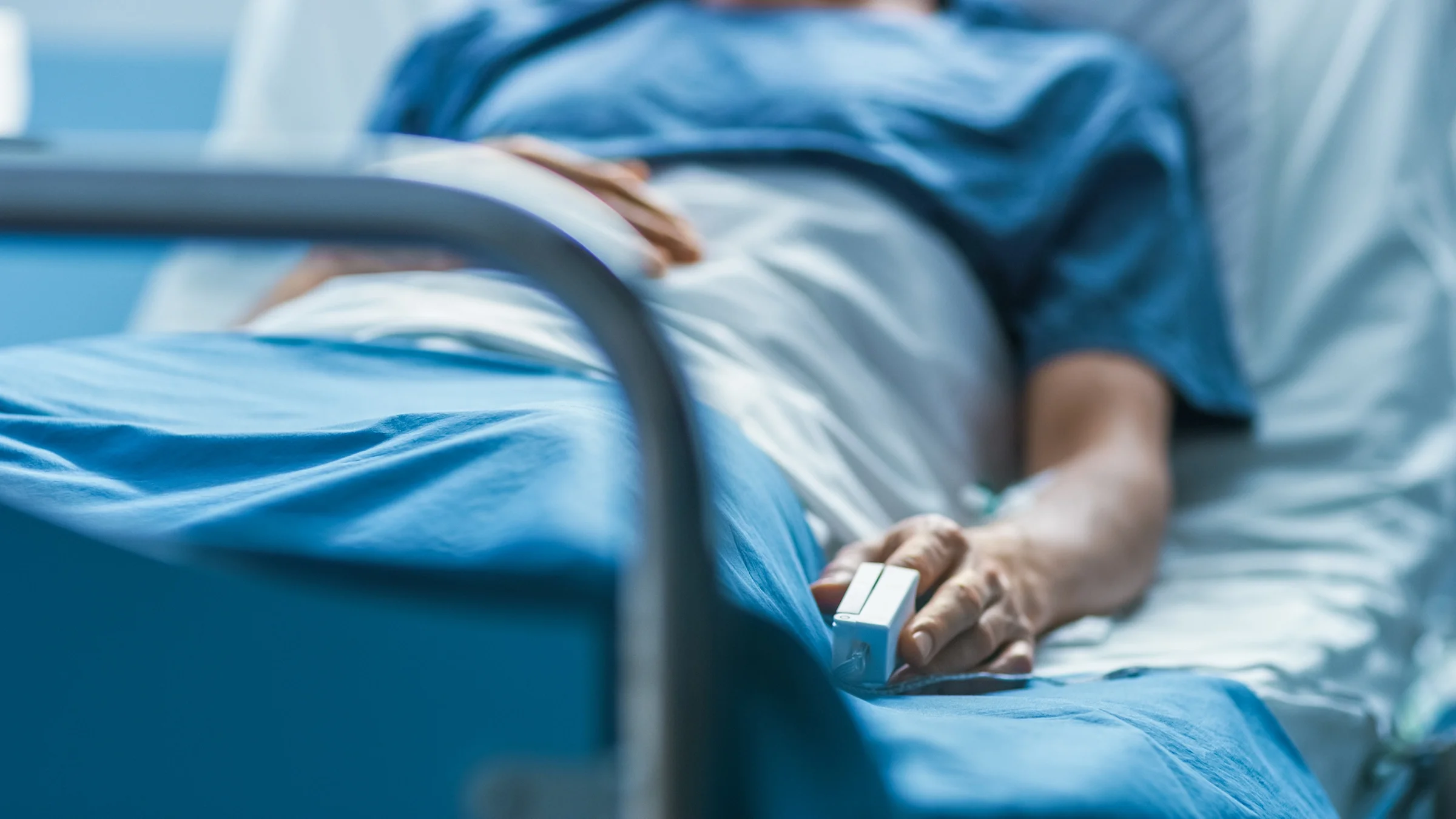 Cropped shot of a person in a hospital gown in a hospital room.