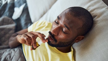 Pharmacy: man using nasal spray in bed 1292130213