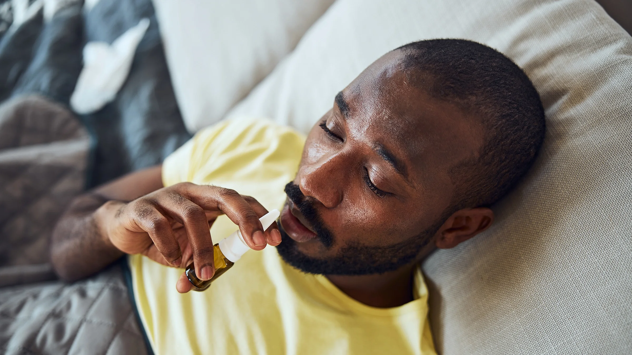 Man using nasal spray in bed