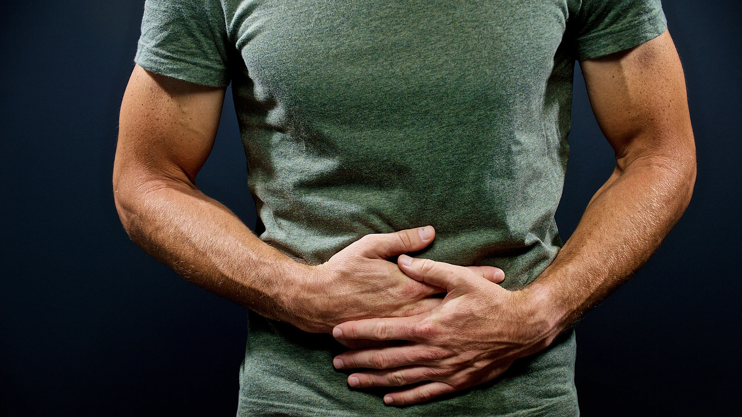 Cropped shot of a man holding his stomach in pain. 